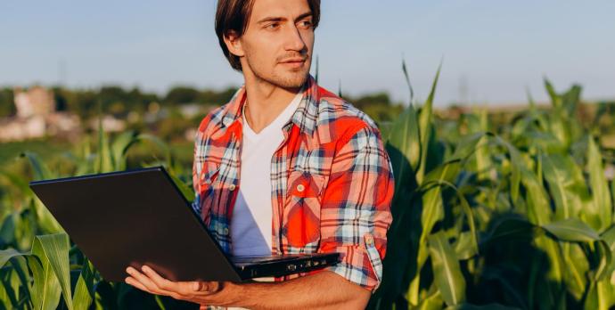 Man in fields with computer